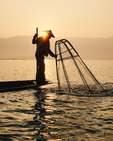 Inle Lake, Myanmar - Feb 16, 2016. Intha man using the unique methods of rowing and catching fish on Inle Lake (Shan State).のeditorial素材