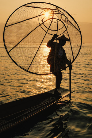 Inle Lake, Myanmar - Feb 16, 2016. Intha man using the unique methods of rowing and catching fish on Inle Lake (Shan State).のeditorial素材