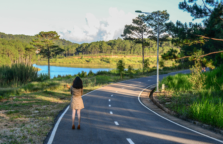 A woman walking on street with many pine trees in Dalat, Vietnam.のeditorial素材