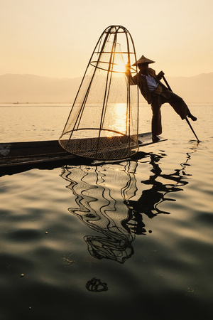 Inle Lake, Myanmar - Feb 16, 2016. Intha man using the unique methods of rowing and catching fish on Inle Lake (Shan State).のeditorial素材