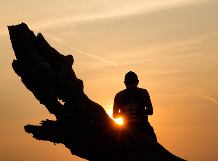 Mandalay, Myanmar - Feb 20, 2016. Man sitting on the tree and looking at sunset in Mandalay, Myanmar.のeditorial素材