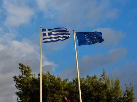 Greek flag and blue European Union flags under the blue sky.の写真素材