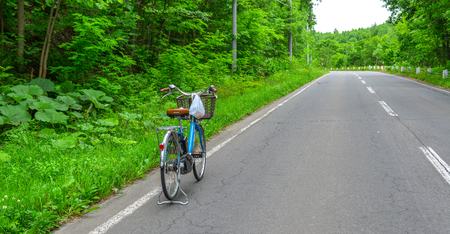 Furano, Japan - Jul 1, 2019. Bicycle on the road with many trees at summer day in Furano, Hokkaido, Japan.のeditorial素材