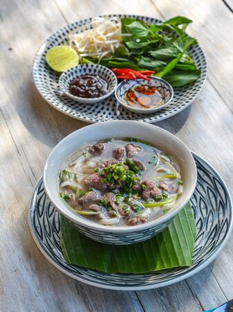 Tasty beef noodles soup served with fresh vegetables (Vietnamese Pho Bo).