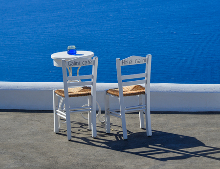 Santorini, Greece - Oct 4, 2018. Two chairs with table on the terrace with sea view in Santorini Island, Greece.のeditorial素材