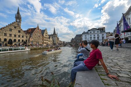 Ghent, Belgium - Oct 6, 2018. People sitting and relaxing on Leie Riverbank. Ghent is the Belgium most beautiful city, rich in history, and attracting tourists.の写真素材