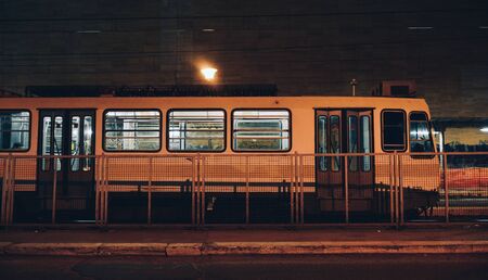 A train standing at a small roofless train station at night.