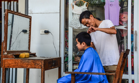 Lao Cai, Vietnam - May 28, 2016. Street barber at Bac Ha market in the rural town of Lao Cai near Sapa, Vietnam.のeditorial素材
