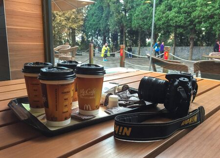 Nanning, China - Nov 1, 2015. Take away hot coffee in paper cup with Nikon DSLR camera at McDonalds...
