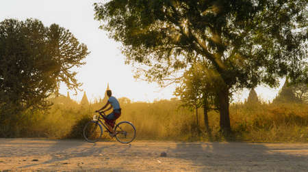 Bagan, Myanmar - Feb 4, 2017. Tourist ride bicycle on a dusty road in the afternoon sunlight in Bagan, Myanmar.のeditorial素材