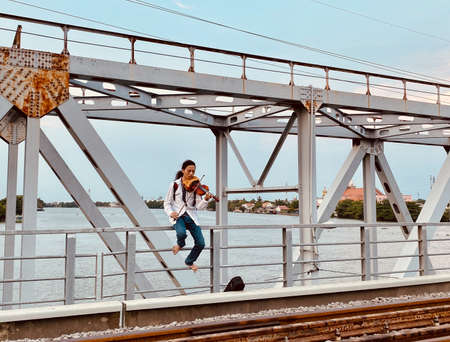 Saigon, Vietnam - Jun 22, 2020. Young man playing violin on Ancient Binh Loi Railway Bridge in Saigon, Vietnam.のeditorial素材