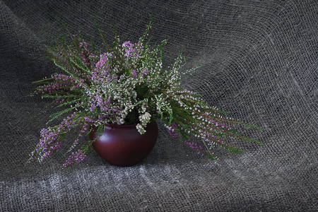 Heather purple and white bouquet. Bouquet of autumn flowers in a ceramic vase. Still life on gray linen background.の写真素材