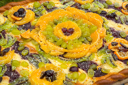 A huge fruit cake with fresh oranges, grapes, kiwi fruit on the tableの写真素材