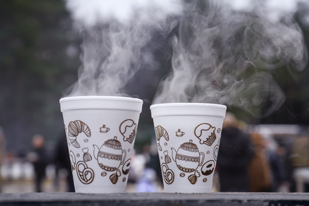 Two cups of hot tea in the cold. Steam rises from the cups with a hot drink. The picture was taken at the city festival winter.の写真素材
