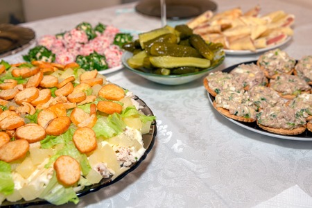 A variety of dishes on the festive table. Chicken salad with pineapples and crackers and other dishes. Holiday food, soft focus.の写真素材