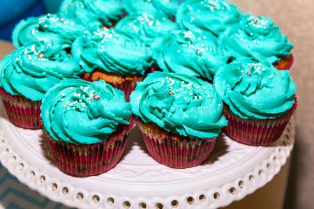 there are delicious tender fresh blue cupcakes, baked and decorated with air cream, lying on a white...
