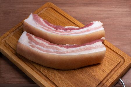 on the cutting Board are two slices of fresh country pork belly. Bacon prepared for saltingの写真素材