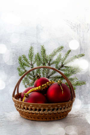Christmas holiday background with red trinket. There is a basket already filled with Christmas balls on a white blurry background, bokeh.の写真素材