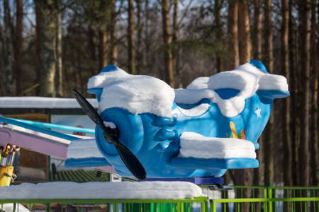 A blue snow-covered airplane is an attraction in a winter city park. Snowy winter in the city park, peace and quiet in winter.の写真素材