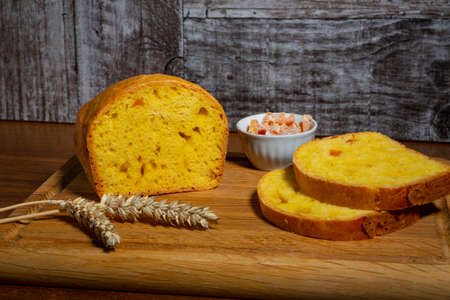 A loaf of bread with candied pumpkin lies on a cutting board on the table. Delicious homemade traditional pie with yellow-orange candied fruits, pie slices, wheat ears.の写真素材