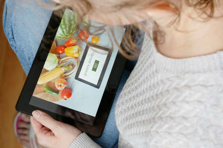 Girl make the order of organic vegetables and fruits with tablet pc, online market, green grocery delivery at home concept, buy online conceptの写真素材