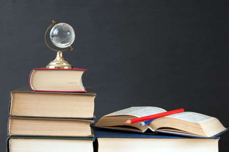 Book pile with apple, globe, pencils and sharpener on the school blackboard. Teacher's day concept