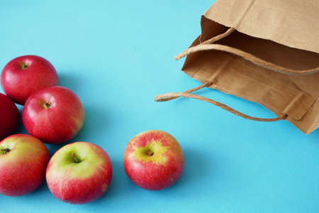 many red apples and paper bag on blue background, green groceryの写真素材