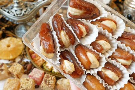 Eastern sweets with nuts, candy, metal vase, dates on wooden background