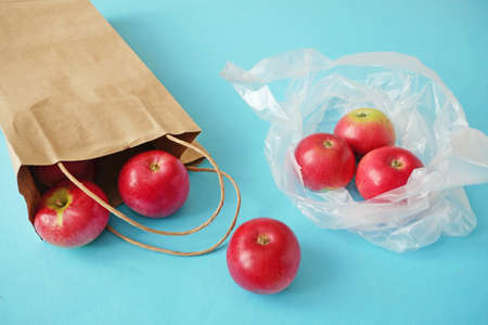 hands put red apples in polythene bag on blue background, zero wasteの写真素材