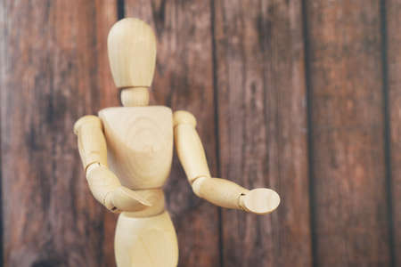 Miniature wooden mannequin stay with outstretched hands on wooden background,の写真素材