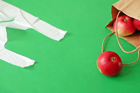 many red apples on paper bag vs polyethylene bag on green background, green grocery concept, zero wasteの写真素材