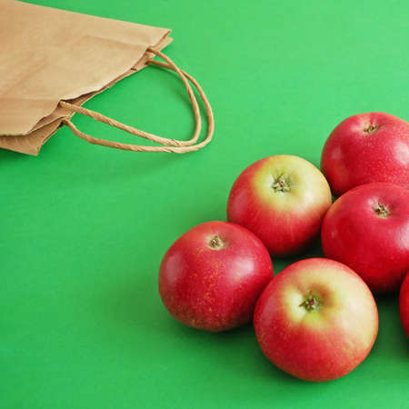 many red apples and paper bag on green background, green grocery concept, zero waste conceptの写真素材