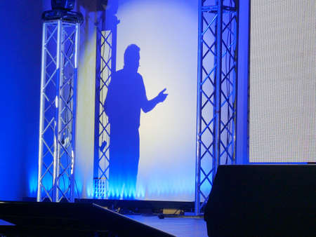 man makes a report on stage at a conference or business seminar, speaker shadow, closeup