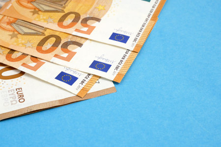 pile of euro on blue background with copy space