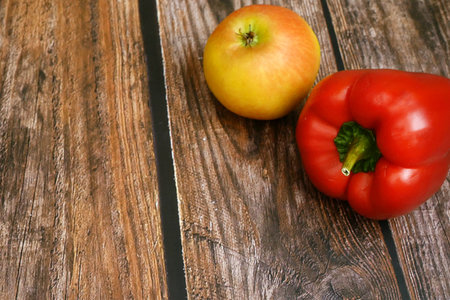 red sweet pepper and yellow apple on wooden background with copy space, closeupの写真素材