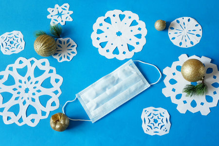 snowflakes paper crafts, handmade new year decoration and medical mask on blue background, closeupの写真素材