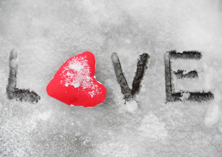 red heart symbol on snowy wooden bench and i love you inscription on the snow, closeupの写真素材
