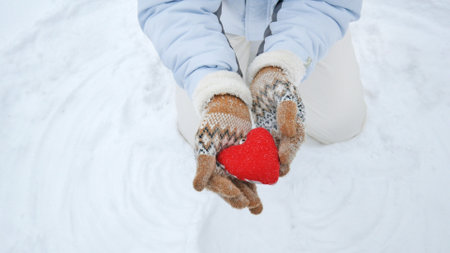 woman hands holding red heart symbol on snow background, closeupの写真素材
