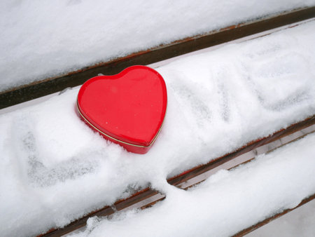red heart symbol on snowy wooden bench and i love you inscription on the snow, closeupの写真素材