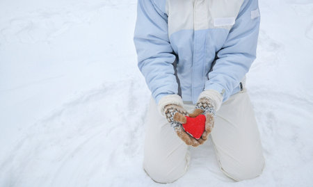 woman hands holding red heart symbol on snow background, closeupの写真素材
