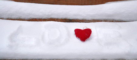 red heart symbol on snowy wooden bench and i love you inscription on the snow, closeup