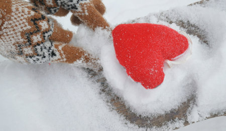 woman hands holding red heart symbol on snow background, closeupの写真素材