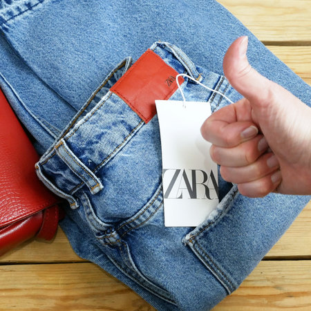 red sweater and jeans on hangers on wooden background with Zara tag, winter sales, closeupのeditorial素材