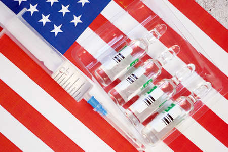 american flag, syringes with coronavirus vaccine, purchase and production vaccine, closeupの写真素材