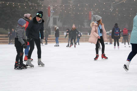 people in skating shoes ice skating outdoor at ice rink, closeupのeditorial素材