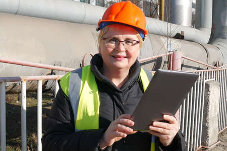 Woman Engineer in the Hard Hat with Laptop near Heavy Industry Manufacturing Factory, closeupの写真素材