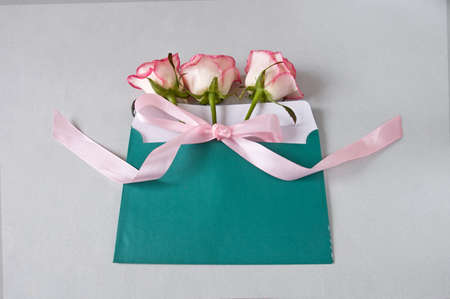 pink pale floral background with roses bunch on table, roses bunch with blank paper card and heart,...