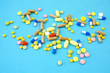 many different medicine pills, drug and capsules on blue background, closeup