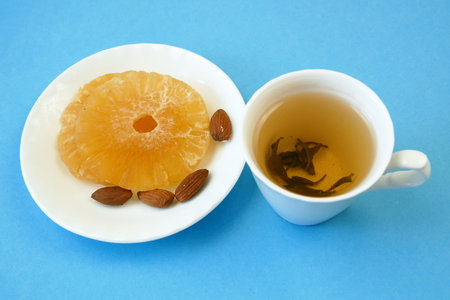 hot tea in cup and ginger slice with nuts on blue background, herbal treatment of fluの写真素材