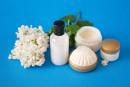 cream cosmetic, soap and extract in lilac cosmetic set with flowers on violet background closeup
